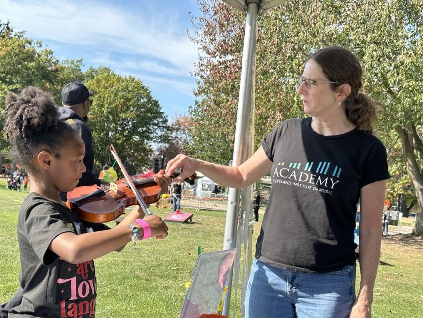Someone from the Cleveland Institute of Music works with a child at Parade the Circle.